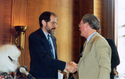 Photo of Professional staff member Jonathan Miller shaking hands with Commissioner John Erickson.
