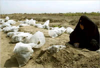 An Iraqi women mourns next to remians of bodies exhumed from a mass grave. AP photo.
