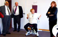 Commissioners Thomas and Sykes hear about JCHE's training room as a resident demonstrates proper use of the equipment